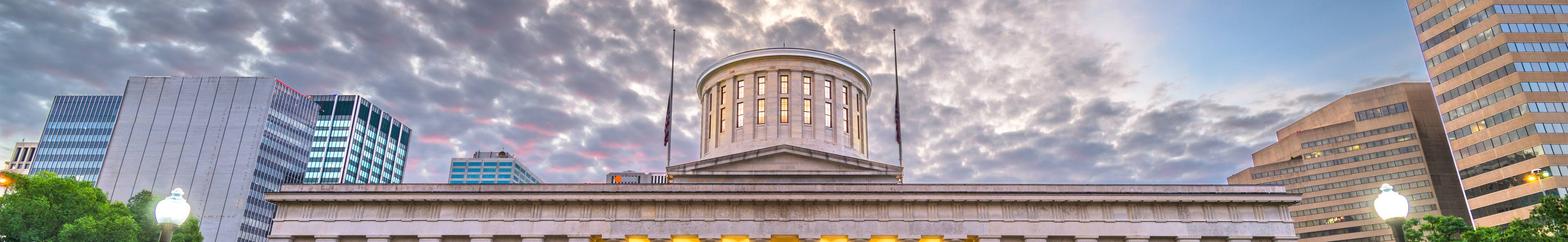 Landscape photo of a government building with a sunset in the background