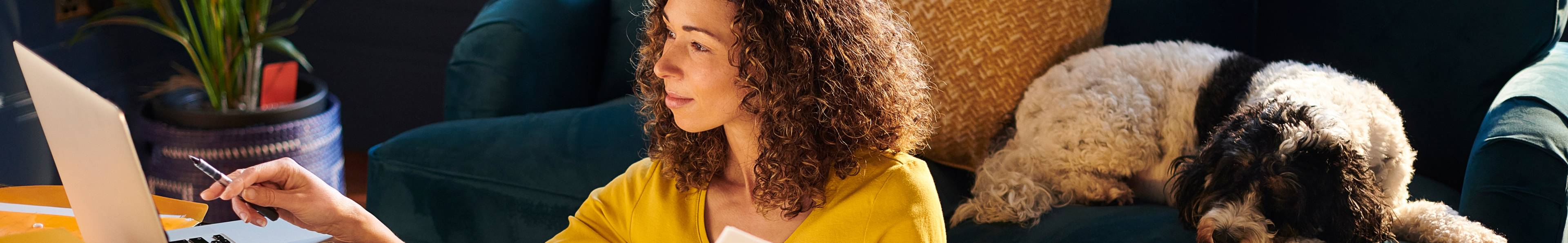 A woman with curly brown hair working on laptop reviewing coverage options.