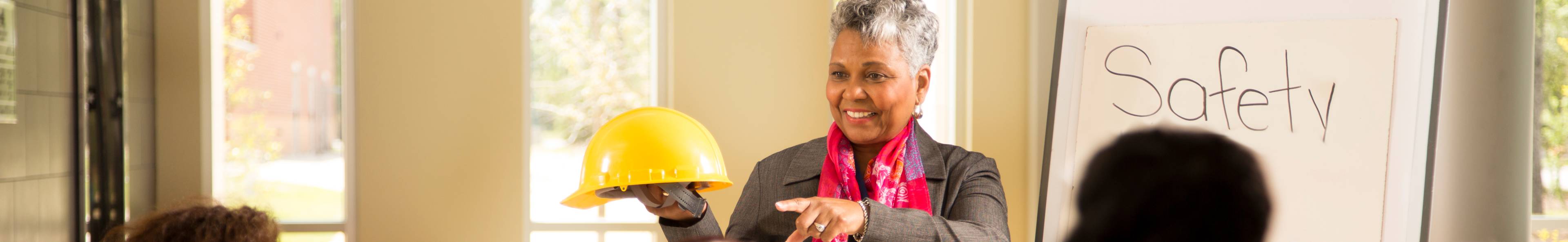 Women holding a safety hat and teaching a class on safety