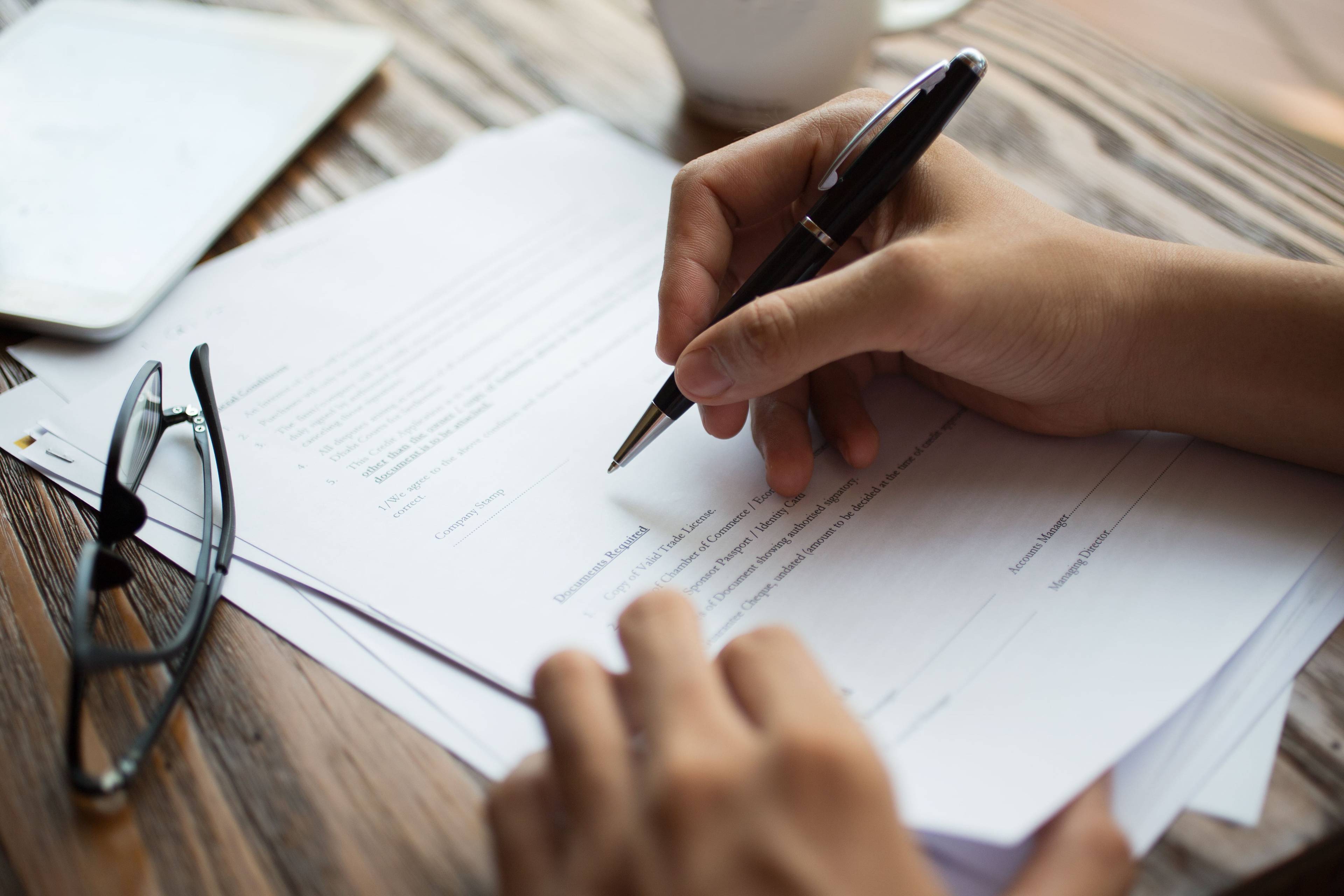 An individual filling out a form with a pen.